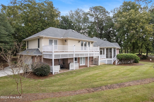 back of property with a deck, a lawn, and a sunroom