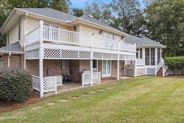 rear view of property featuring a yard, a wooden deck, and a sunroom