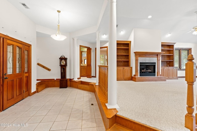 entrance foyer with a healthy amount of sunlight, ornate columns, a fireplace, and light tile patterned floors