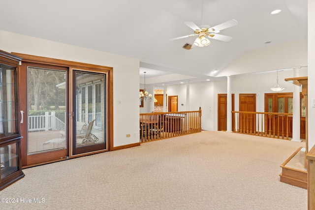 carpeted spare room featuring ceiling fan with notable chandelier, ornate columns, and lofted ceiling