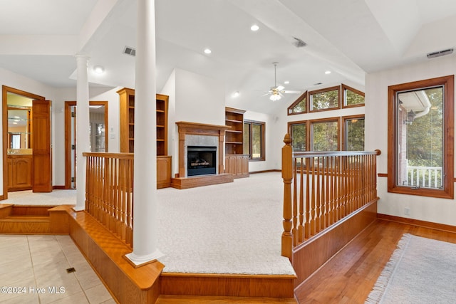 unfurnished living room featuring decorative columns, ceiling fan, vaulted ceiling, and light wood-type flooring