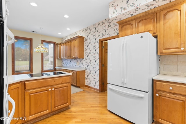 kitchen with white fridge, hanging light fixtures, light hardwood / wood-style floors, and black electric cooktop