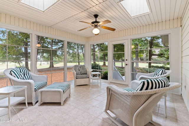 sunroom featuring a skylight, ceiling fan, and wooden ceiling