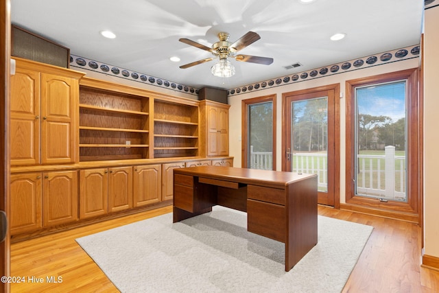 home office with light hardwood / wood-style flooring and ceiling fan