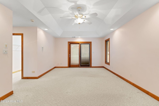 carpeted spare room with ceiling fan and a raised ceiling