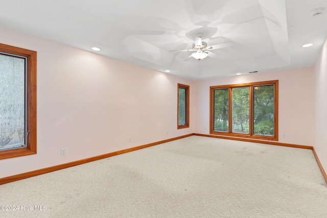 spare room with ceiling fan, a raised ceiling, and carpet floors