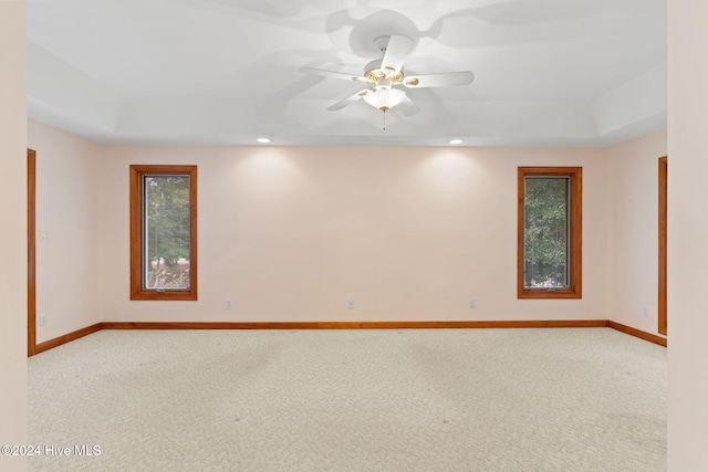 carpeted empty room featuring a raised ceiling and ceiling fan