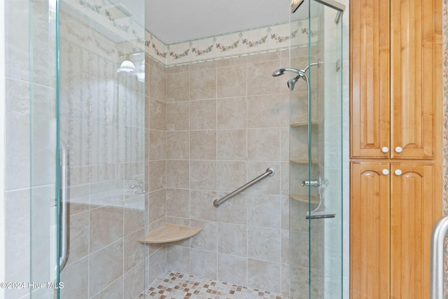 bathroom with a shower with shower door and a textured ceiling