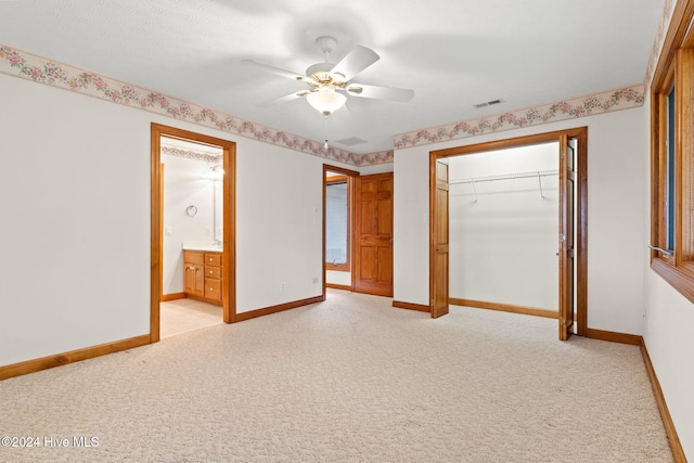 unfurnished bedroom with light carpet, a closet, ensuite bath, and ceiling fan