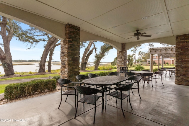 view of patio / terrace with an outdoor stone fireplace, a water view, and ceiling fan