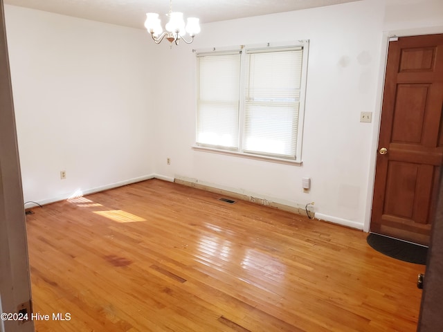 empty room featuring light hardwood / wood-style floors and a notable chandelier