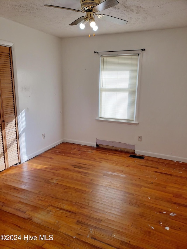 unfurnished room featuring a textured ceiling, light hardwood / wood-style floors, and ceiling fan