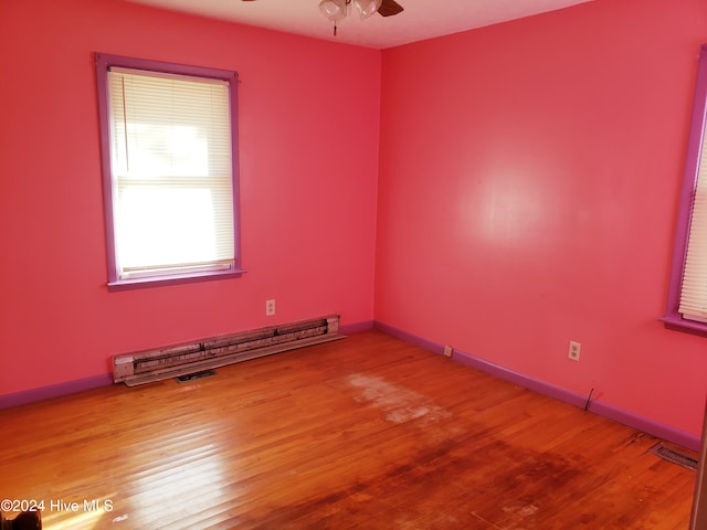 spare room featuring baseboard heating, ceiling fan, and hardwood / wood-style floors