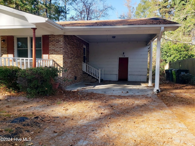 view of exterior entry featuring a porch and a carport