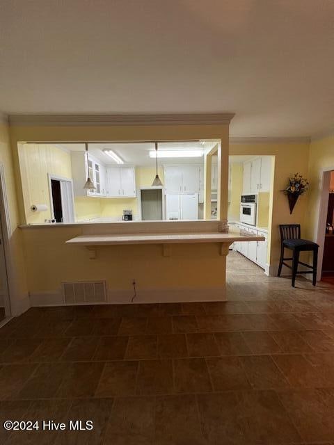 kitchen with a breakfast bar, white appliances, kitchen peninsula, and white cabinets