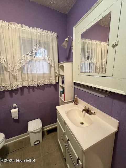 bathroom with tile patterned flooring, vanity, a textured ceiling, and toilet