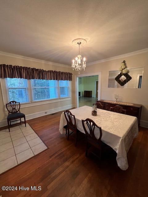 dining area featuring an inviting chandelier, ornamental molding, and hardwood / wood-style flooring