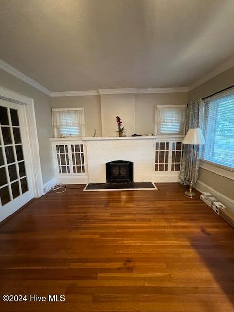 unfurnished living room with hardwood / wood-style floors and crown molding