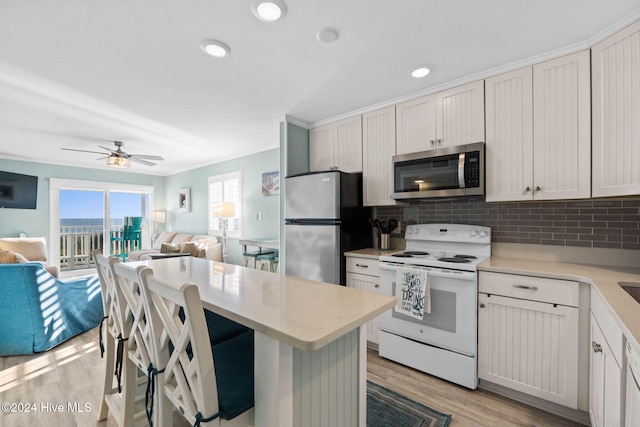 kitchen featuring stainless steel appliances, white cabinetry, tasteful backsplash, and light wood-type flooring