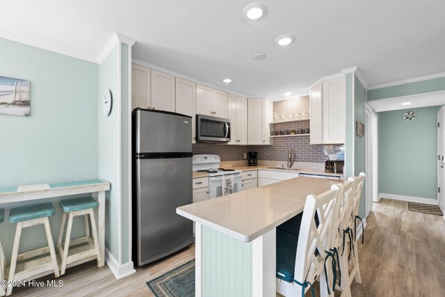 kitchen featuring white cabinetry, sink, stainless steel appliances, and a kitchen bar