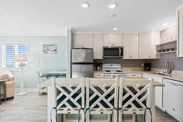 kitchen with tasteful backsplash, appliances with stainless steel finishes, sink, and light wood-type flooring