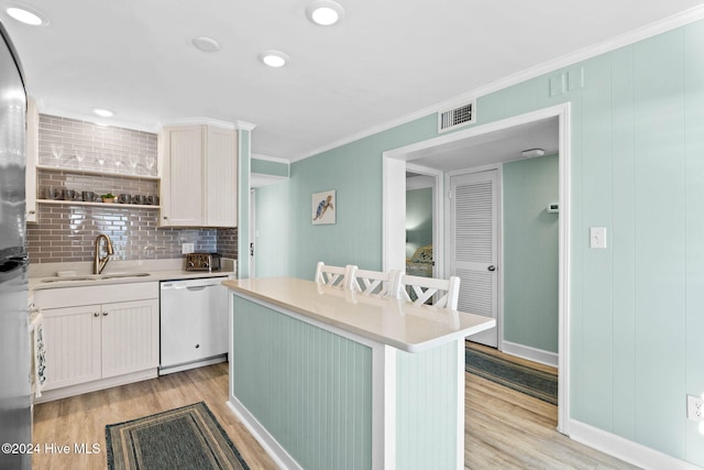 kitchen featuring sink, a center island, white dishwasher, light hardwood / wood-style floors, and white cabinets