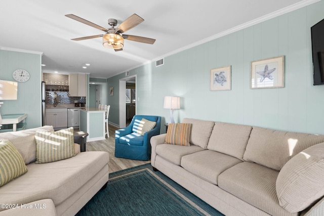 living room featuring ornamental molding, ceiling fan, and light hardwood / wood-style floors