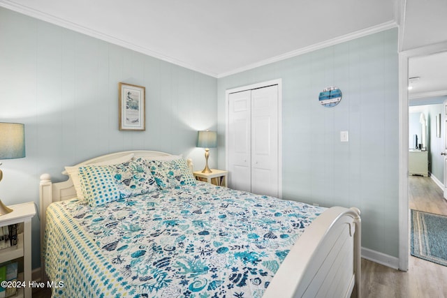 bedroom with hardwood / wood-style flooring, ornamental molding, and a closet