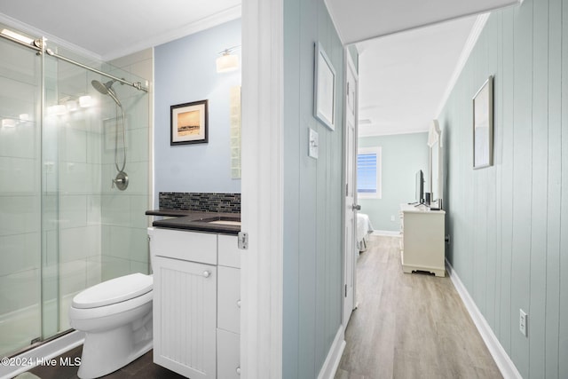 bathroom featuring toilet, ornamental molding, vanity, hardwood / wood-style flooring, and decorative backsplash