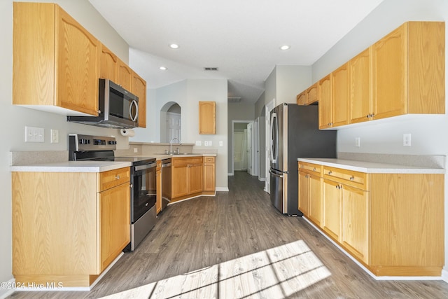 kitchen with stainless steel appliances, vaulted ceiling, sink, light brown cabinets, and hardwood / wood-style flooring