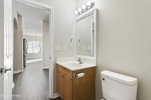 bathroom with hardwood / wood-style floors, vanity, a textured ceiling, and toilet