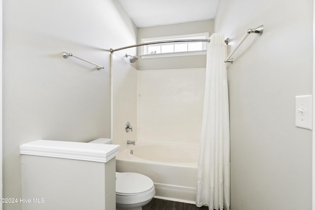 bathroom with hardwood / wood-style floors, shower / bathtub combination with curtain, and toilet