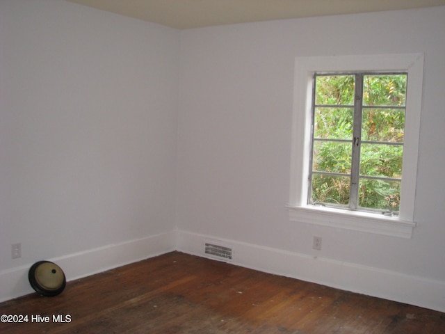 empty room with dark hardwood / wood-style flooring and a healthy amount of sunlight