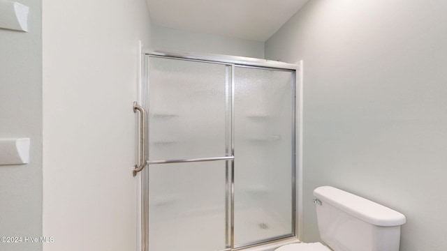 bathroom featuring walk in shower and toilet