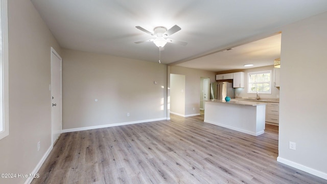 unfurnished living room with light hardwood / wood-style flooring, ceiling fan, and sink