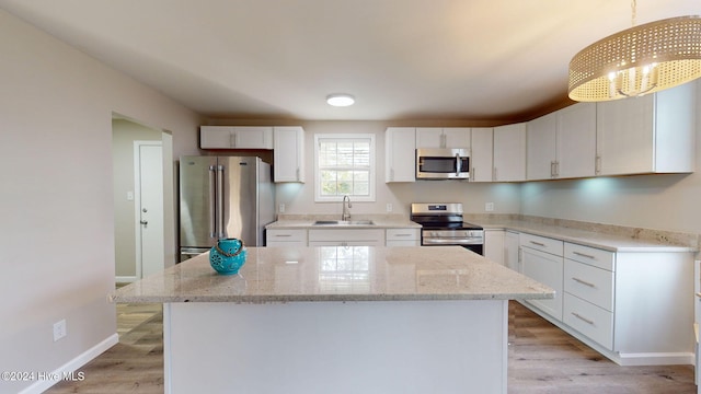 kitchen featuring appliances with stainless steel finishes, decorative light fixtures, a kitchen island, and sink