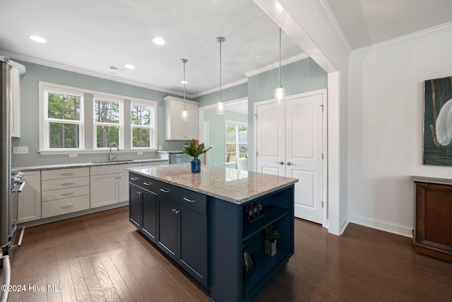 kitchen with a sink, white cabinets, dark wood-type flooring, a center island, and ornamental molding
