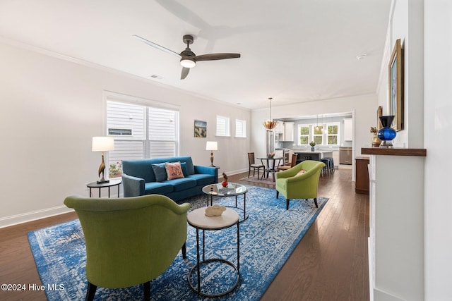 living room with baseboards, ceiling fan, dark wood-type flooring, and crown molding