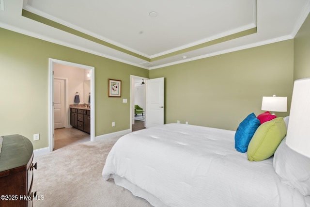 bedroom with a raised ceiling, carpet floors, ornamental molding, baseboards, and connected bathroom