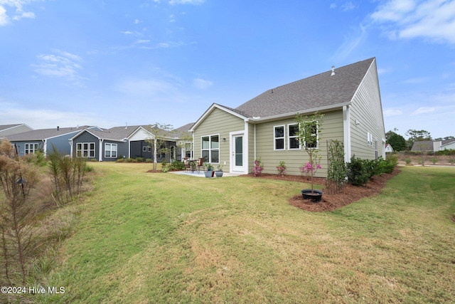 back of house with a patio area, a yard, and roof with shingles