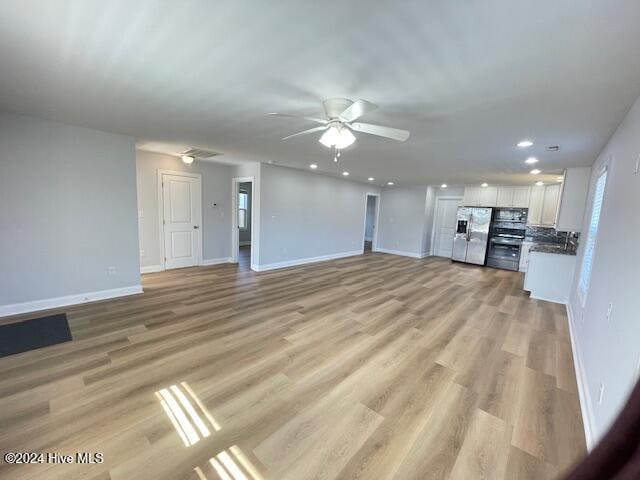 unfurnished living room featuring ceiling fan and light hardwood / wood-style floors