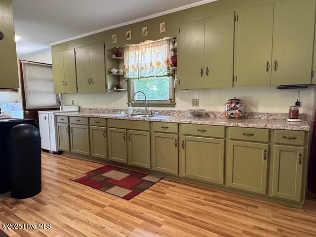 kitchen with light wood finished floors, open shelves, ornamental molding, and a sink