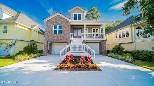 view of front of house with a garage, covered porch, and french doors