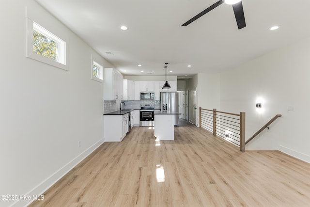 kitchen with dark countertops, backsplash, appliances with stainless steel finishes, white cabinets, and a sink