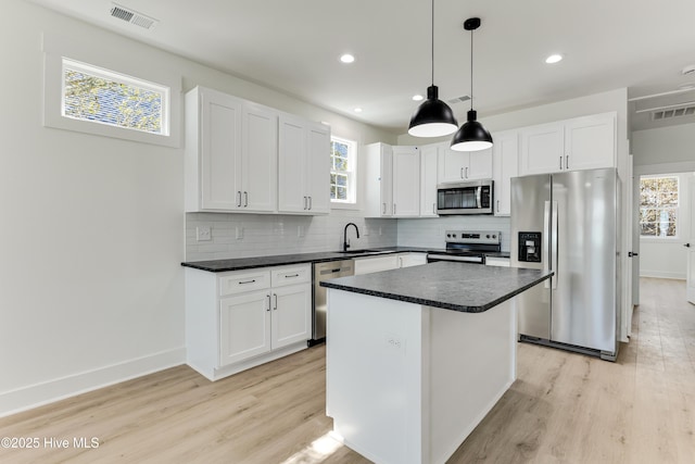 kitchen featuring stainless steel appliances, a sink, visible vents, and decorative backsplash