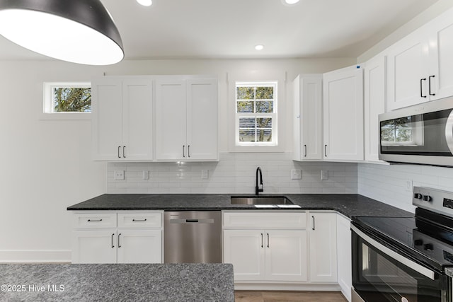 kitchen with a healthy amount of sunlight, white cabinetry, stainless steel appliances, and a sink