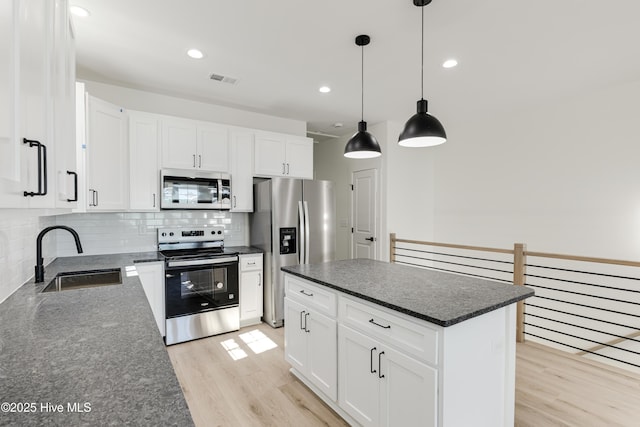 kitchen with stainless steel appliances, a sink, light wood-style flooring, and tasteful backsplash