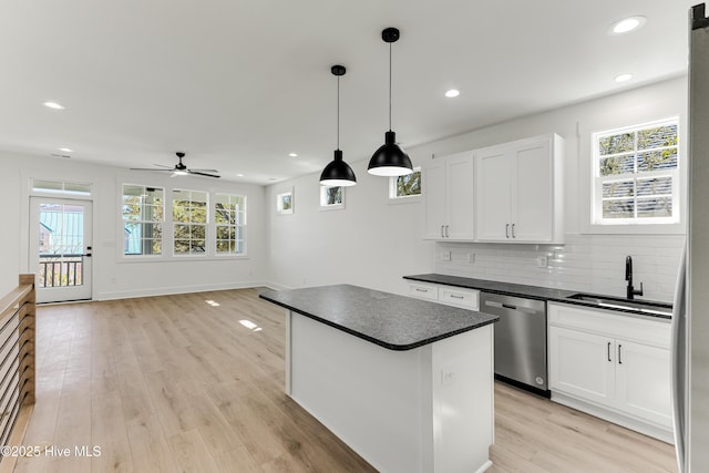 kitchen with decorative backsplash, dark countertops, light wood-style flooring, stainless steel dishwasher, and a sink