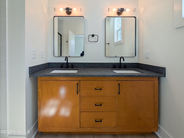 bathroom with double vanity, a sink, and baseboards