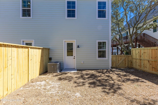 rear view of house with a gate, a fenced backyard, and central AC unit